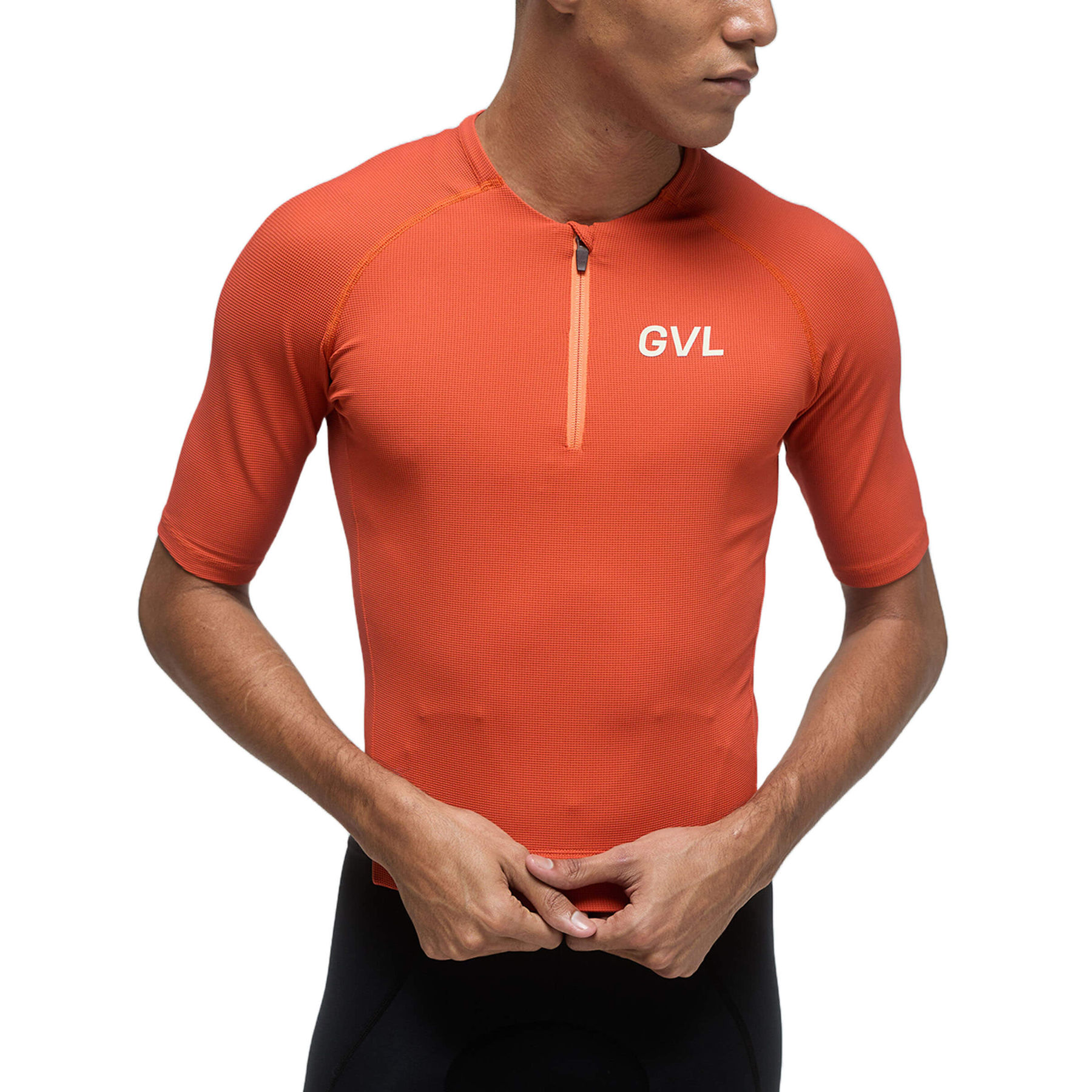 Front view of a person wearing a pumpkin-colored Givelo Modern Classic jersey, emphasizing the half-zip closure, the waffle texture fabric, and the 'GVL' logo on the chest, blending functionality with a unique style.