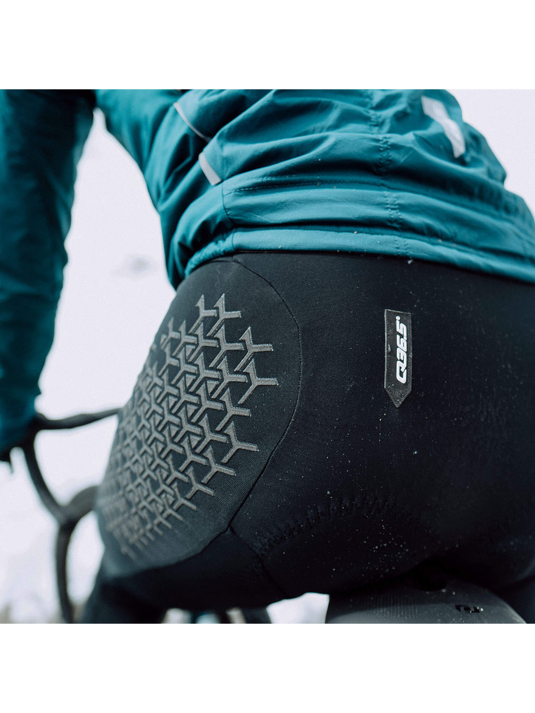 Cyclist wearing Q36.5 Grid Skin Winter Bib Tights showing rear protective design.