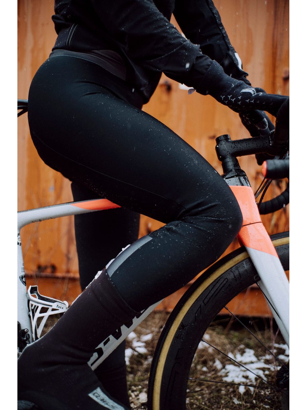 Detailed view of Q36.5 Winter Bib Tights worn by a cyclist, showcasing the minimal seam design and pre-shaped fit, with snowflakes visible on the fabric.