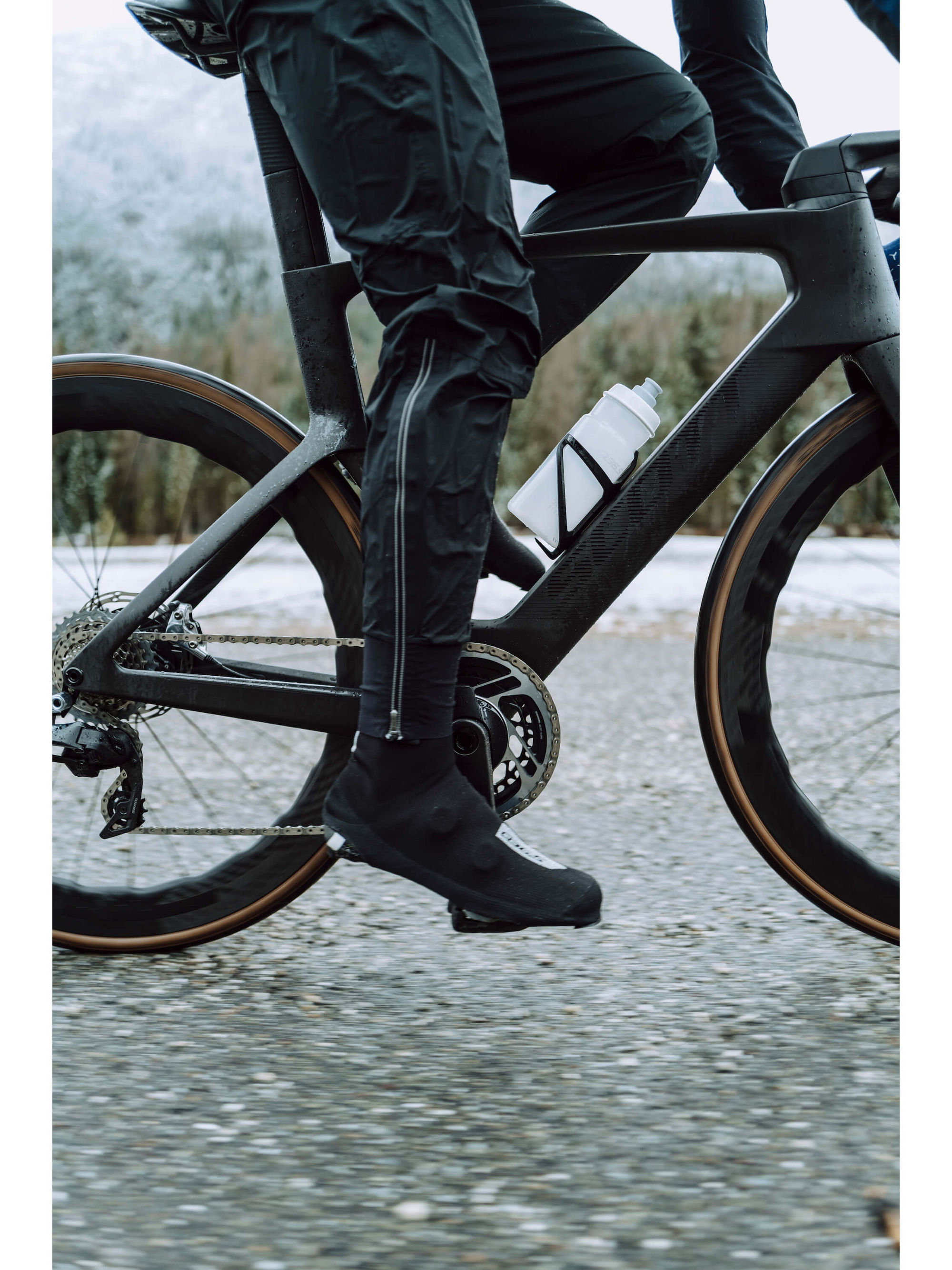 Q36.5 Rain Overpants worn while cycling, showcasing ease of movement and fit.