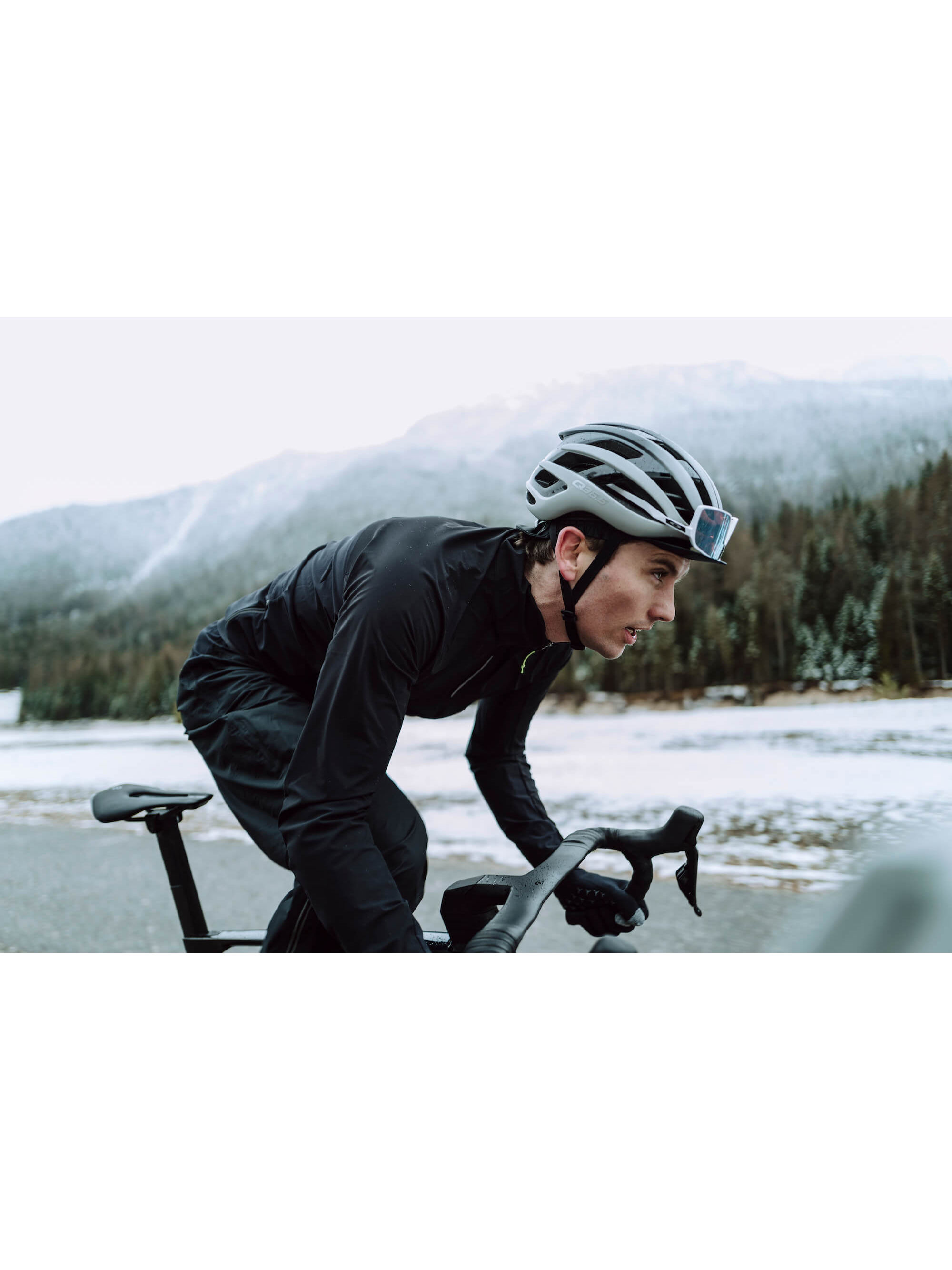 Action shot of a cyclist in the black Q36.5 Bat Shell Long Sleeve Jersey, showcasing its practicality and performance in wet and cold conditions.