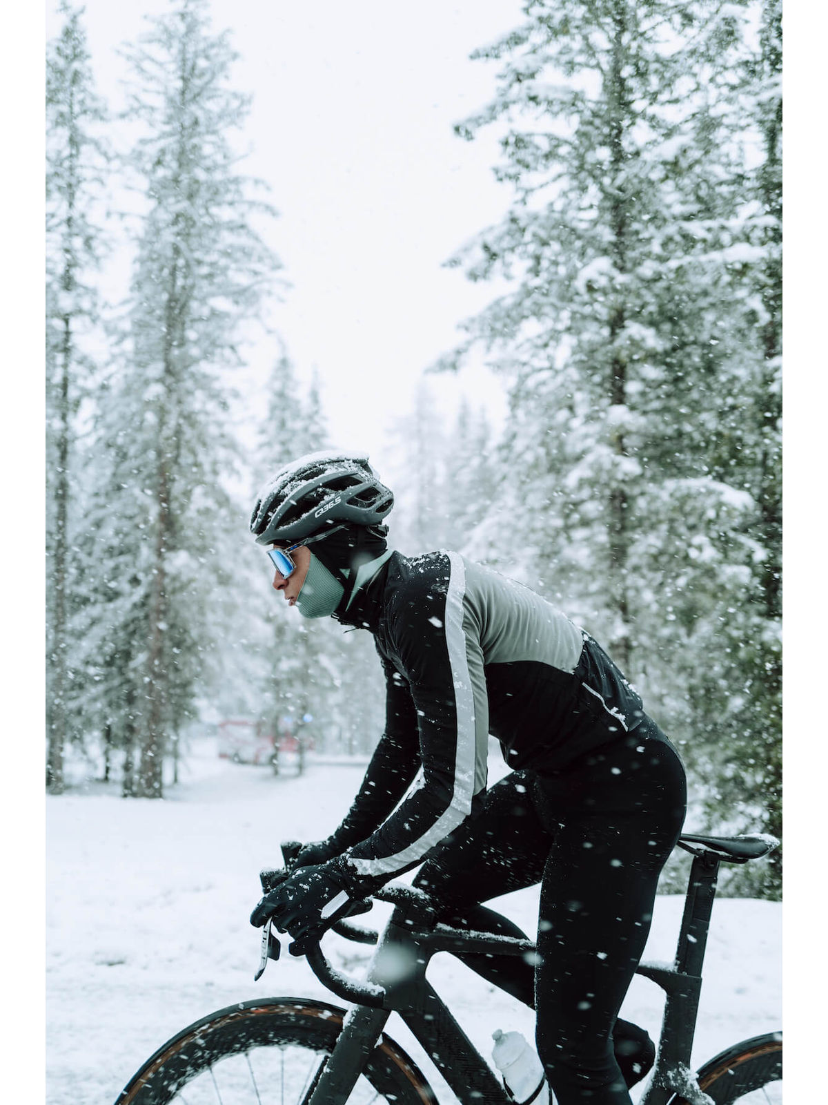 Side view of a cyclist riding in the snow, equipped with Q36.5 black winter gloves.