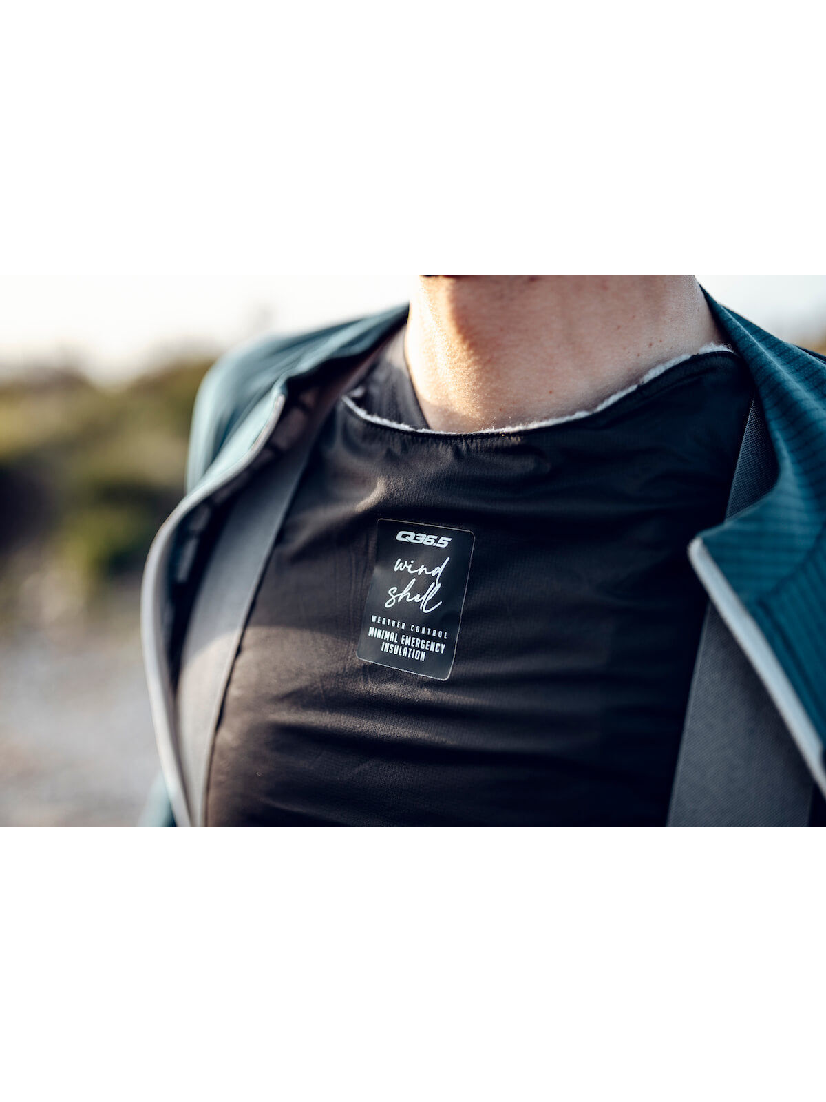 Close-up of the Q36.5 Wind Shell worn by a cyclist, focusing on the emergency insulation's fit and functionality.