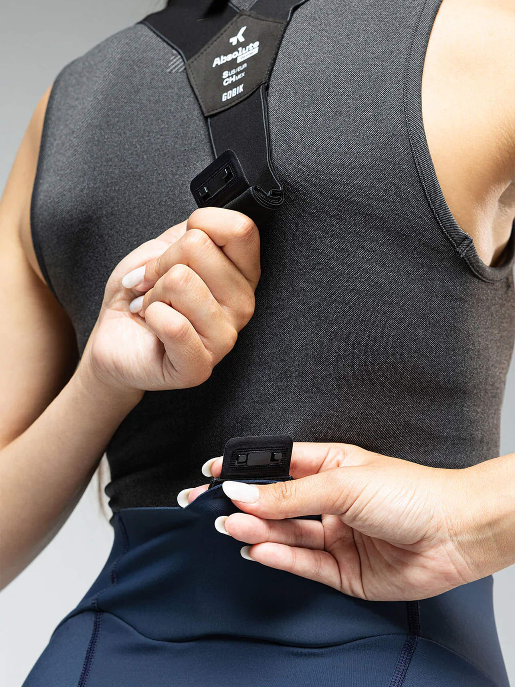 Close-up of the upper back of the woman in the cycling gear showing the fastening mechanism of the GOBIK absolute 6.0 bib tight.