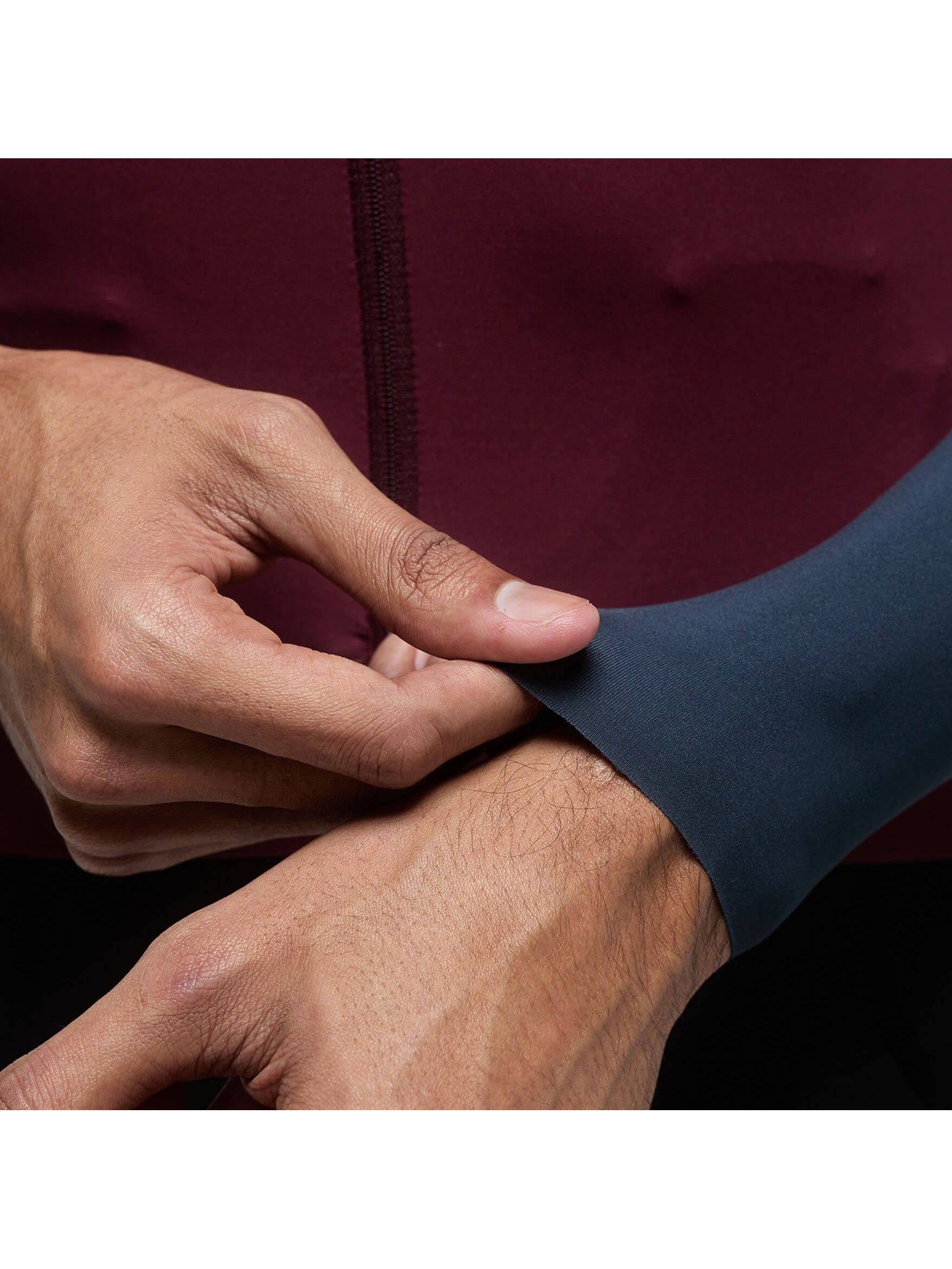 A close-up on the wrist of a rider wearing the Givelo Modern Classic long sleeve jersey, highlighting the snug fit and the transition from the burgundy sleeve to the grey panel.