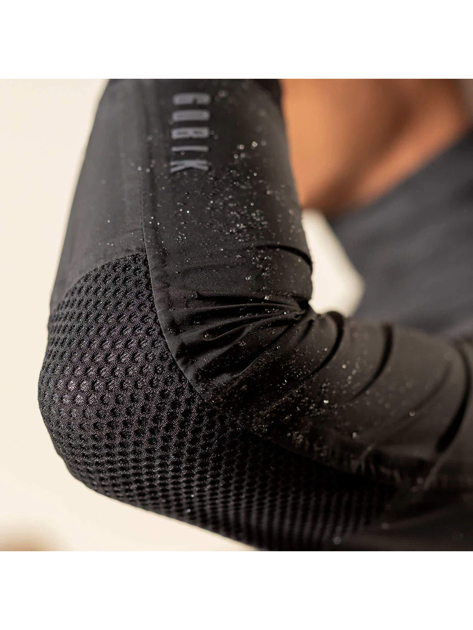 Detail of the GOBIK rain jacket's sleeve, showing water-resistant fabric and secure cuff design for rainy rides.