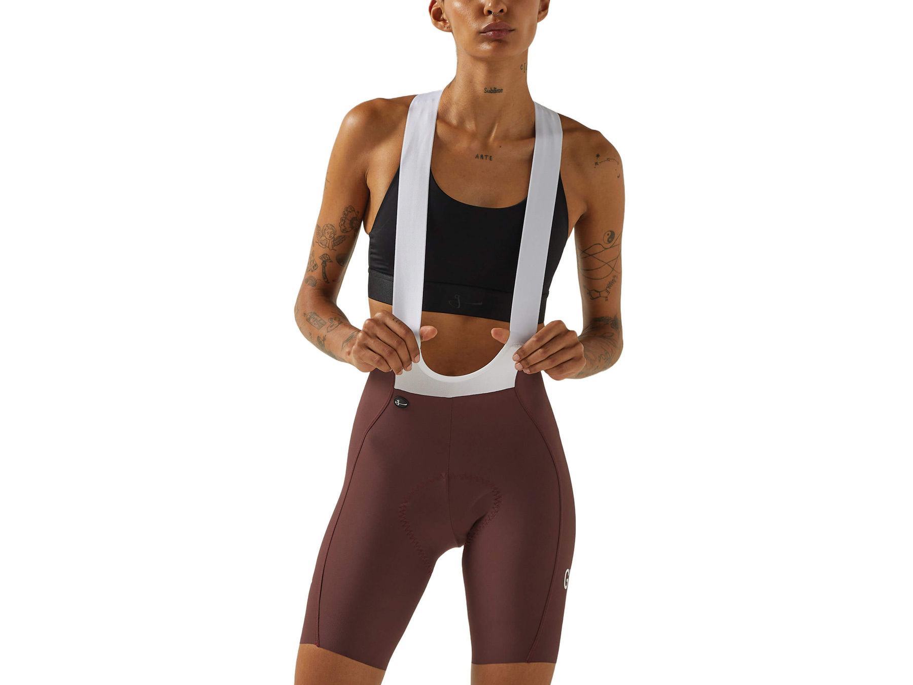 Front view of a woman wearing wine-colored Givelo HD Pro Bib Shorts with a black sports bra and white shoulder straps. The design shows a contoured fit for cycling comfort and performance.