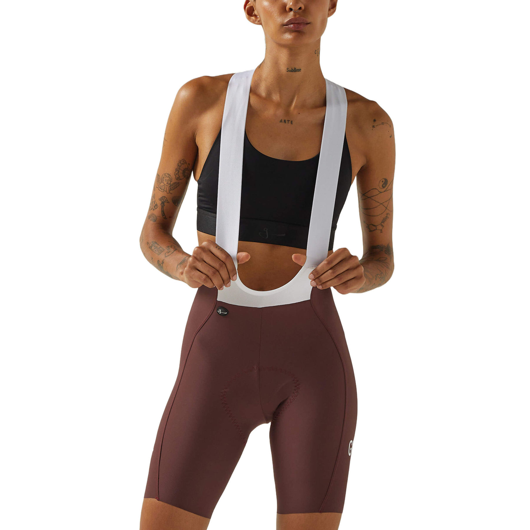 Front view of a woman wearing wine-colored Givelo HD Pro Bib Shorts with a black sports bra and white shoulder straps. The design shows a contoured fit for cycling comfort and performance.