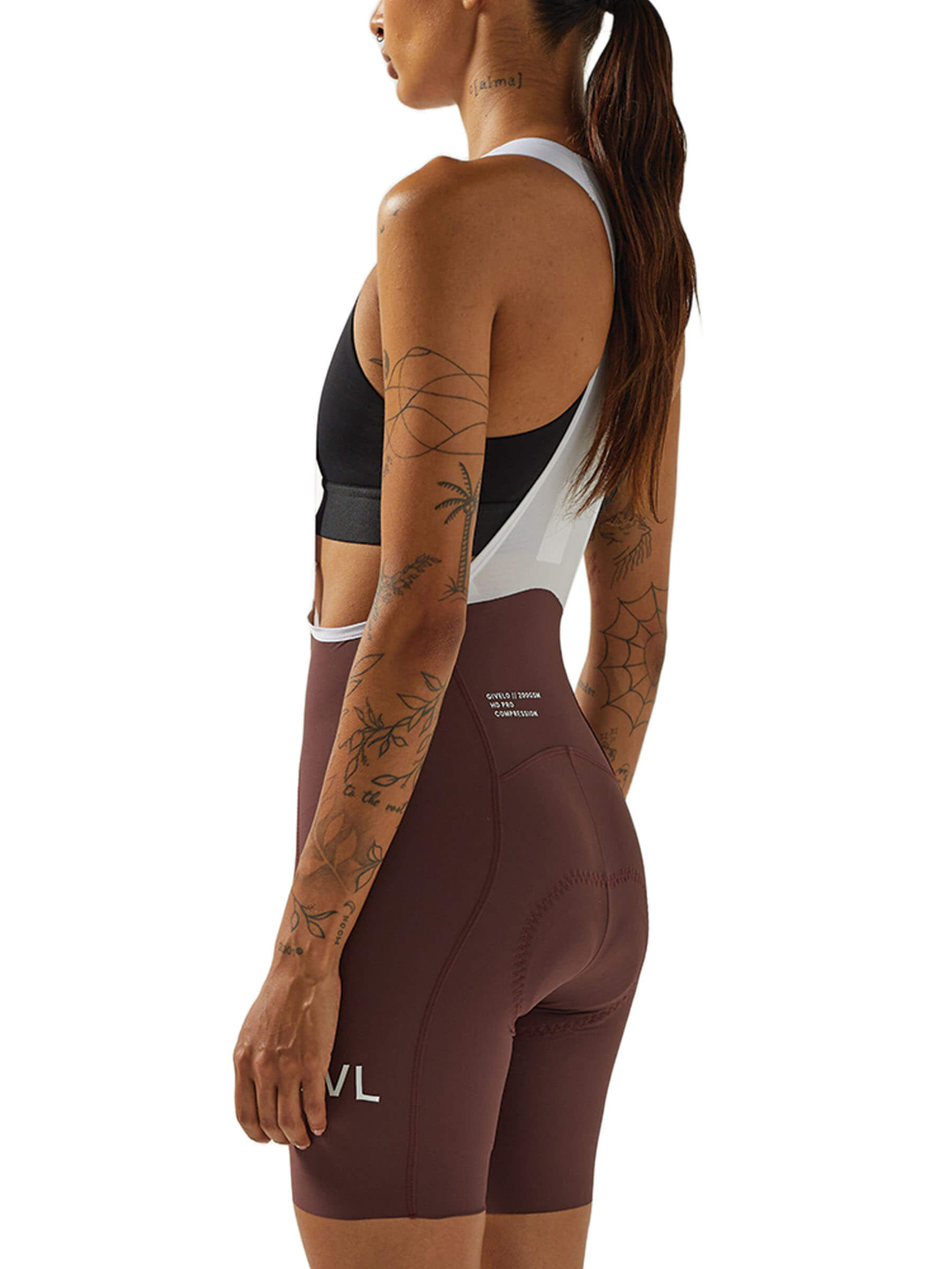 Side view of a woman in wine-colored Givelo HD Pro Bib Shorts, demonstrating the snug fit and the 