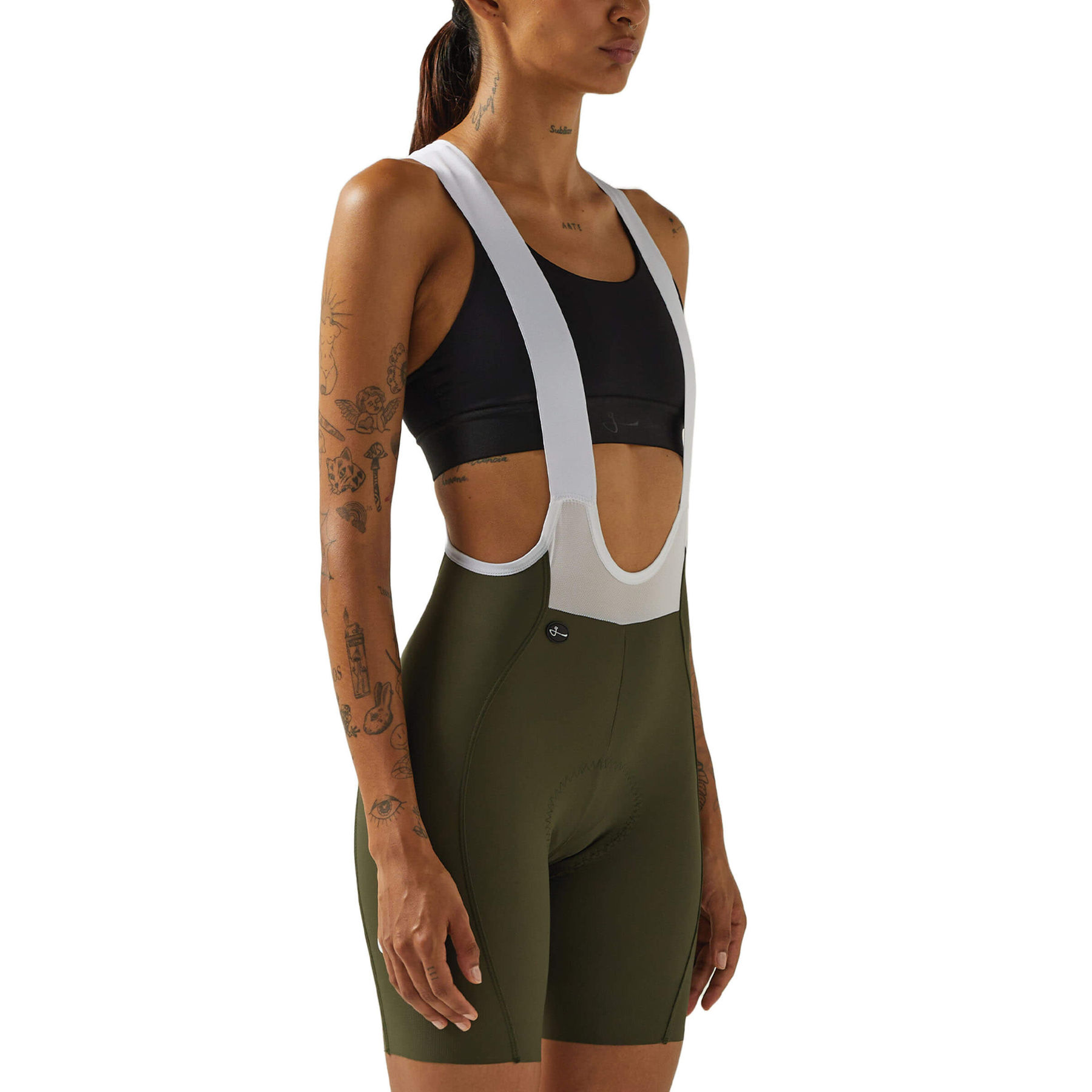 Close-up side view of a woman's lower torso wearing black Givelo HD Pro Bib Shorts, showing the detailed stitching and fabric texture, along with the white shoulder straps and the brand's button logo near the hip.