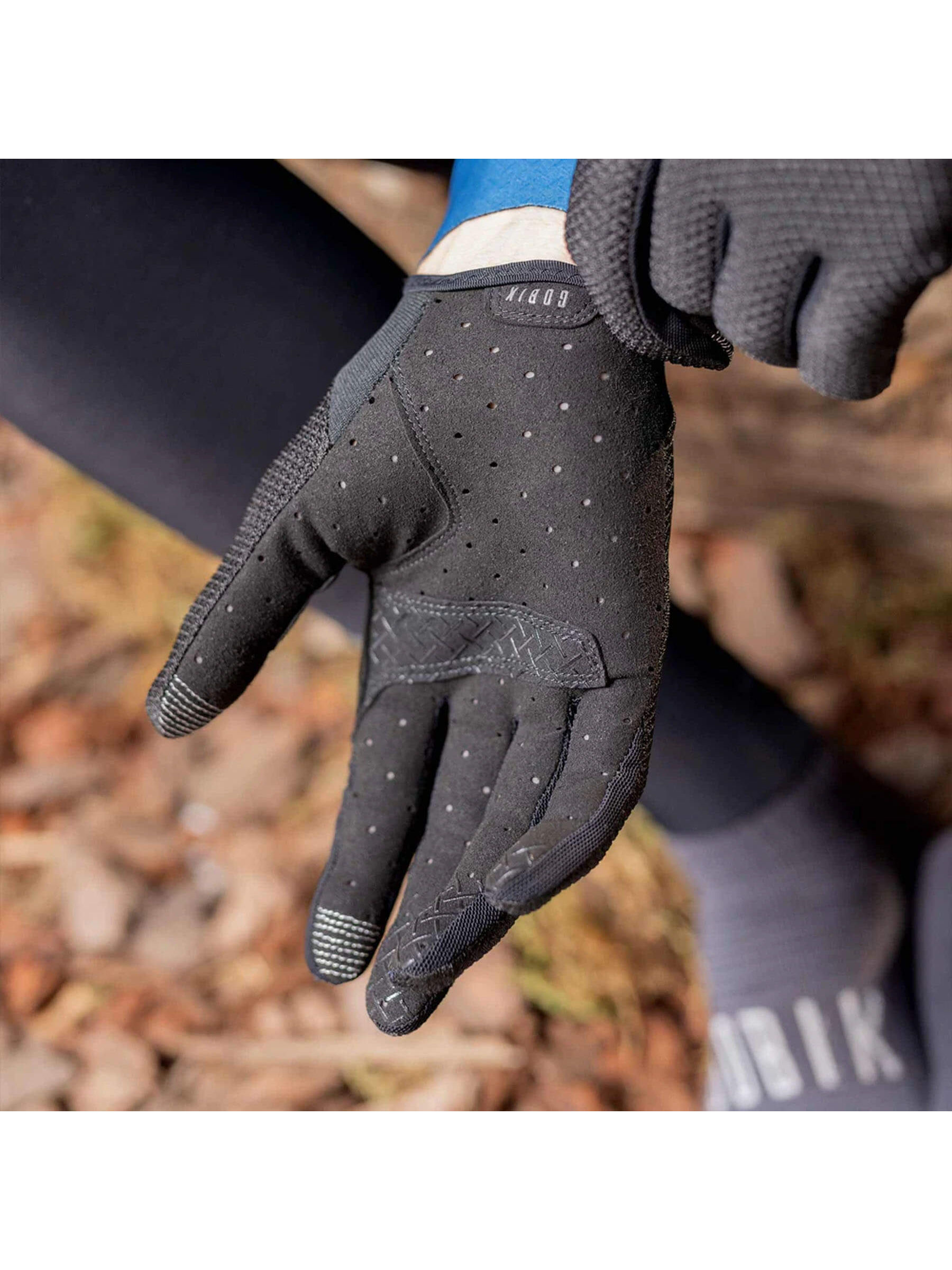 Cyclist's hands in GOBIK Lynx Gloves in black, showing the interaction with bike components.