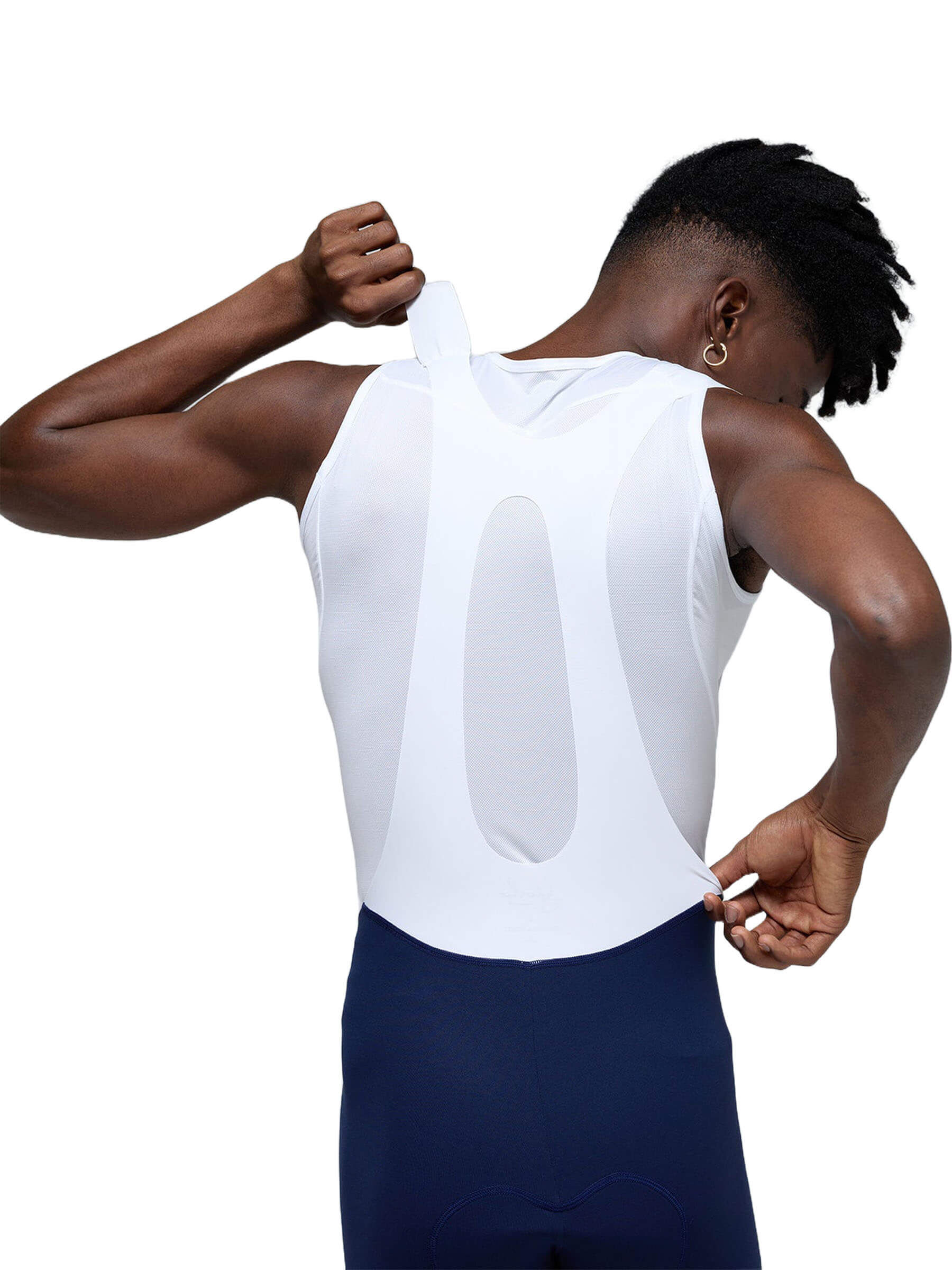 Rear view of the man, slightly turned, pulling the back of his white bib shorts, with a focus on the breathable fabric structure.