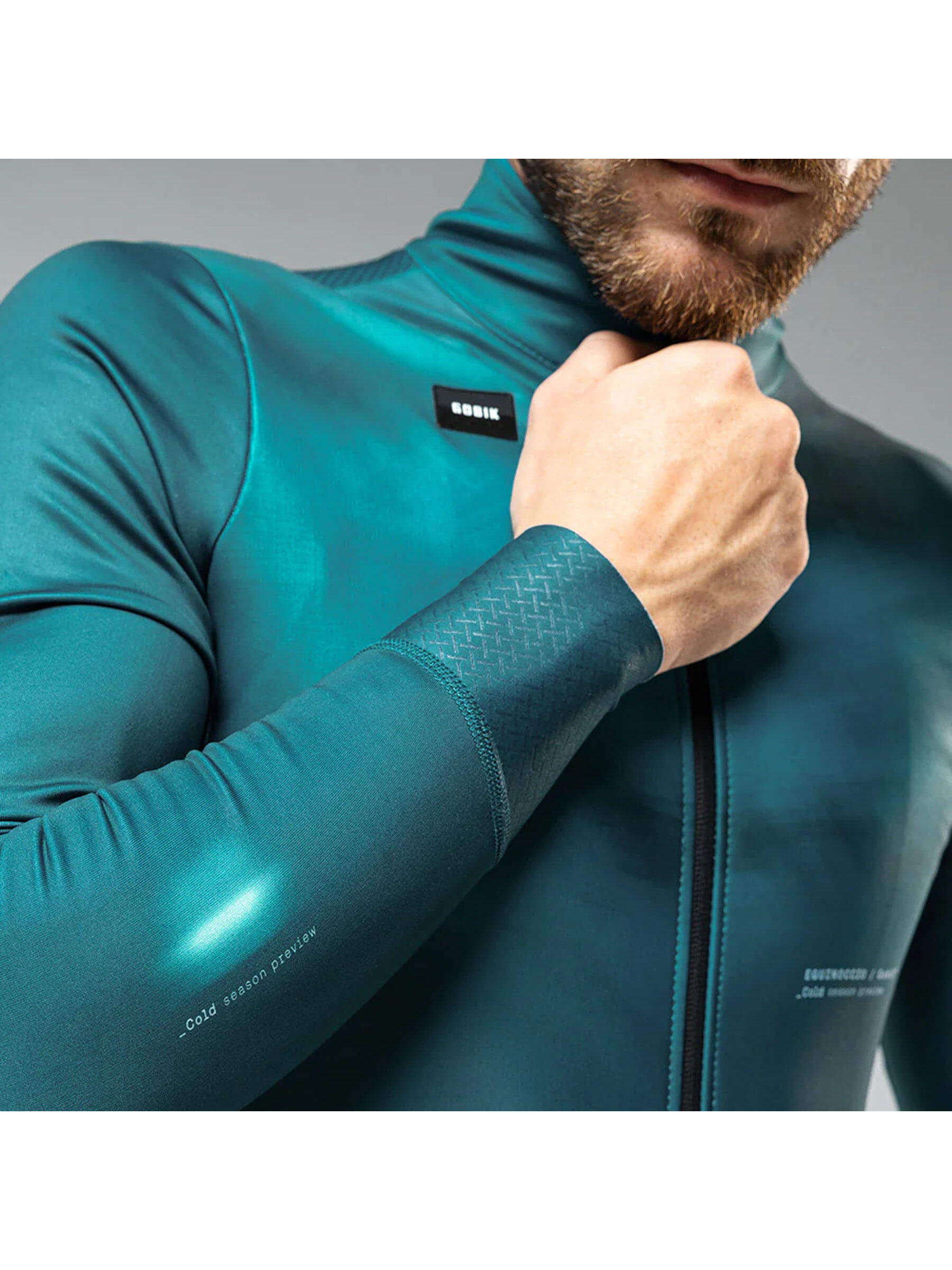 Athletic fit of GOBIK Skimo Pro Hydro jacket for men in equinox teal with secure zip pockets and flexible sleeves for winter cycling.