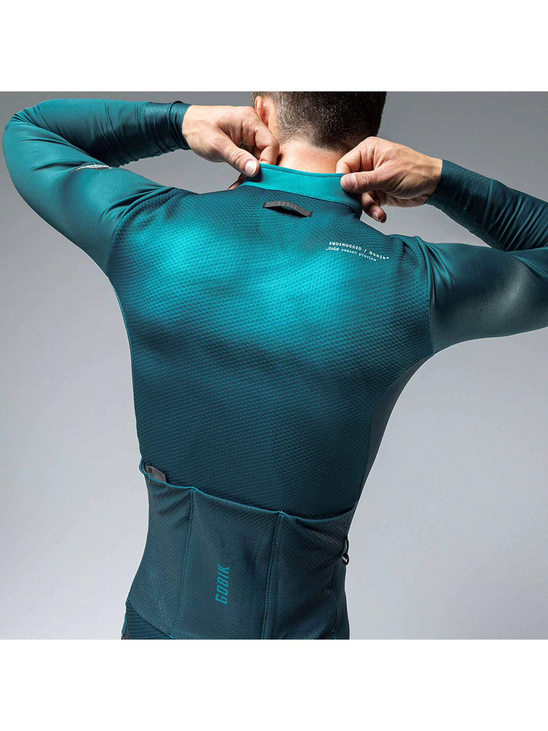 Rear view of GOBIK Skimo Pro Hydro jacket in teal, with reflective details and three back pockets for storage during low temperatures.
