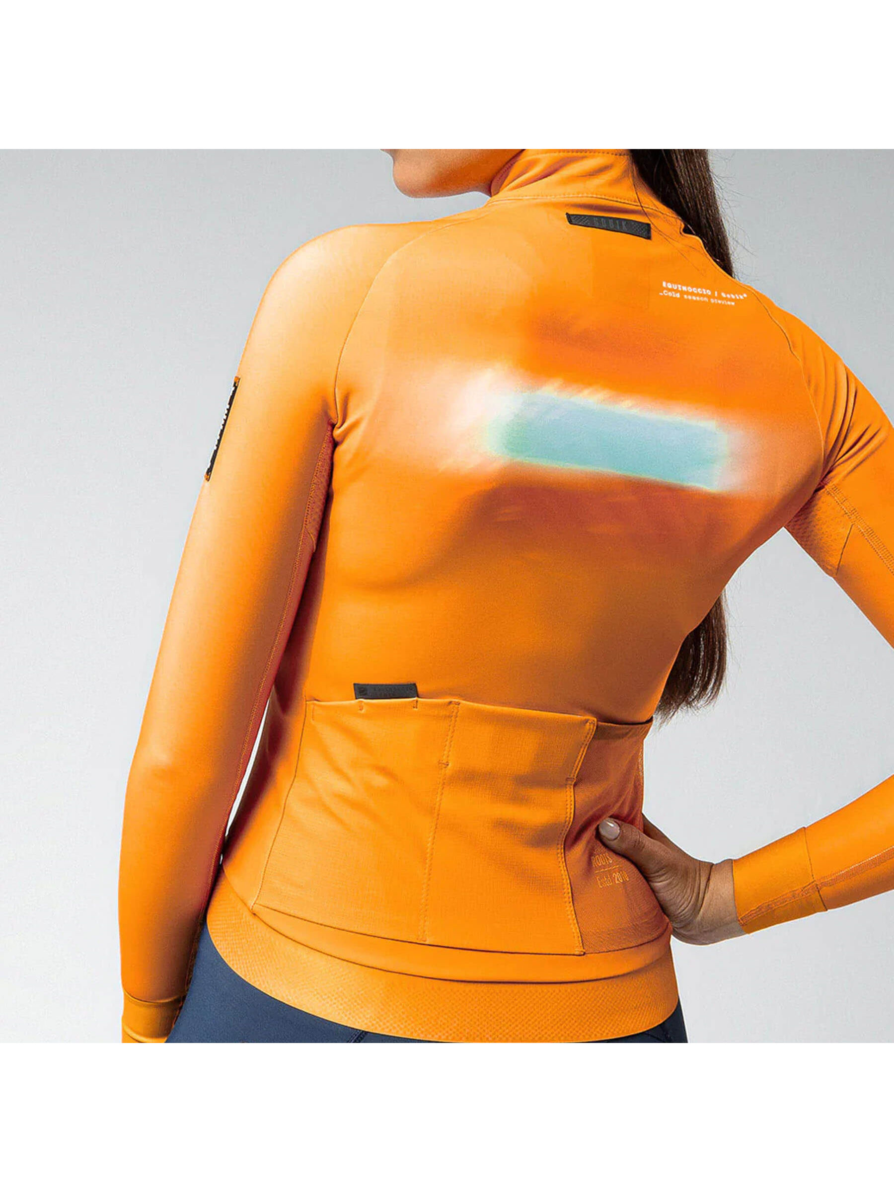 Rear view of madras orange Hyder jacket showing dual back pockets with GRS system and additional side mesh pocket.